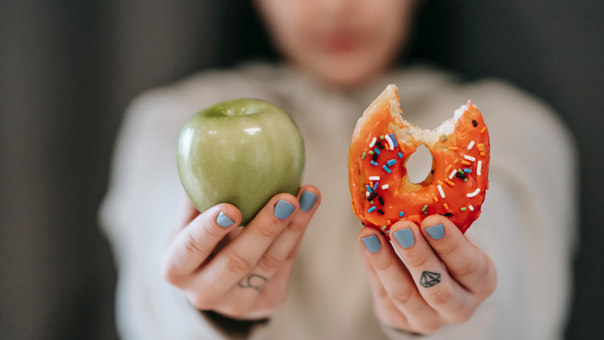 woman holding an apple and donut