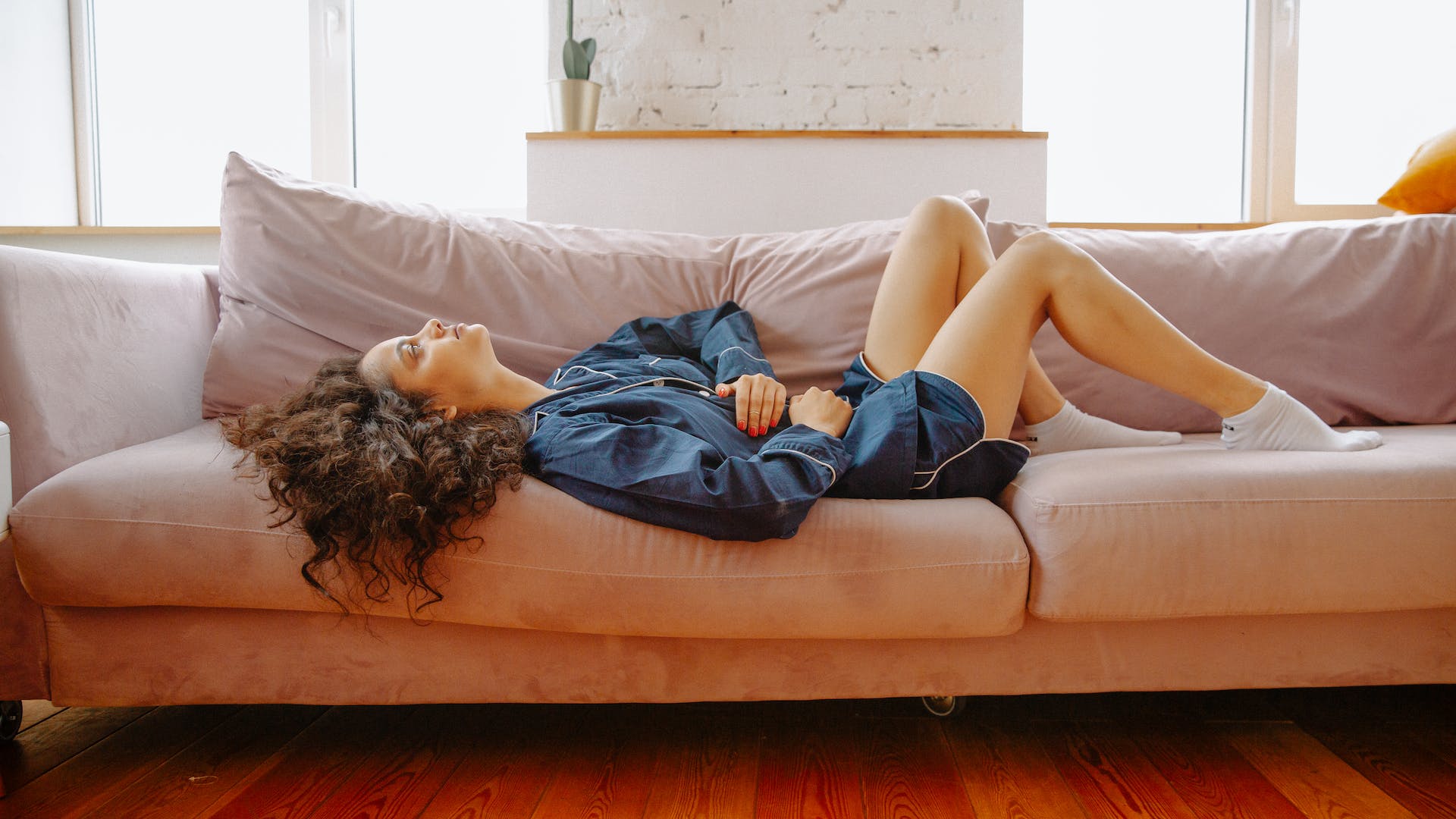 woman lying on sofa from stomach ache